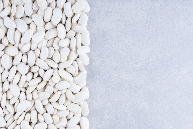 Navy beans neatly gathered into a rectangular arrangement on marble surface