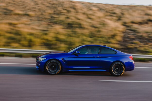 Navy blue sport sedan on the road. Side view.