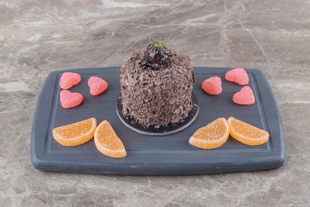 Navy board with chocolate cake and marmelade bundles on marble surface