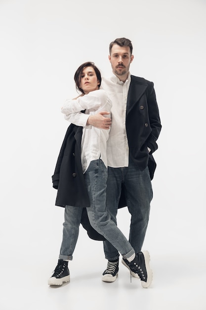 Near by. Trendy fashionable couple isolated on white studio background. Caucasian woman and man posing in basic minimal black stylish clothes. Concept of relations, fashion, beauty, love. Copyspace.