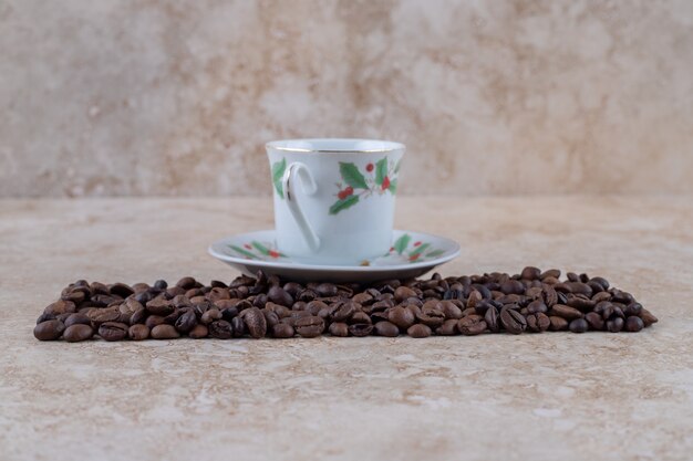 Un mucchio pulito del chicco di caffè e una tazza di caffè su un piattino