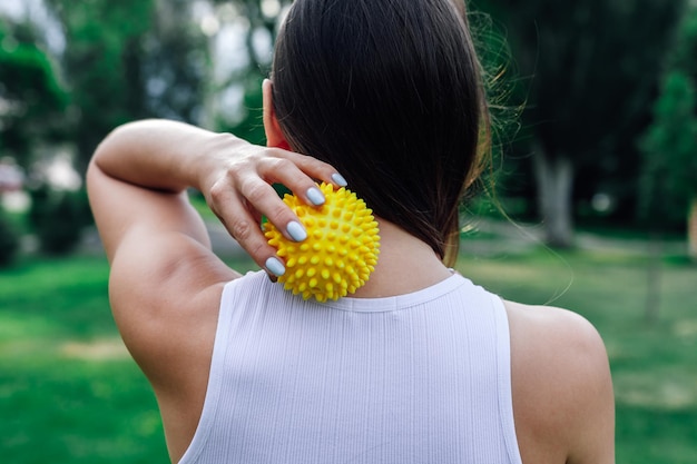 Neck massage with spiky yellow massage ball for muscle pain relieve and myofascial release