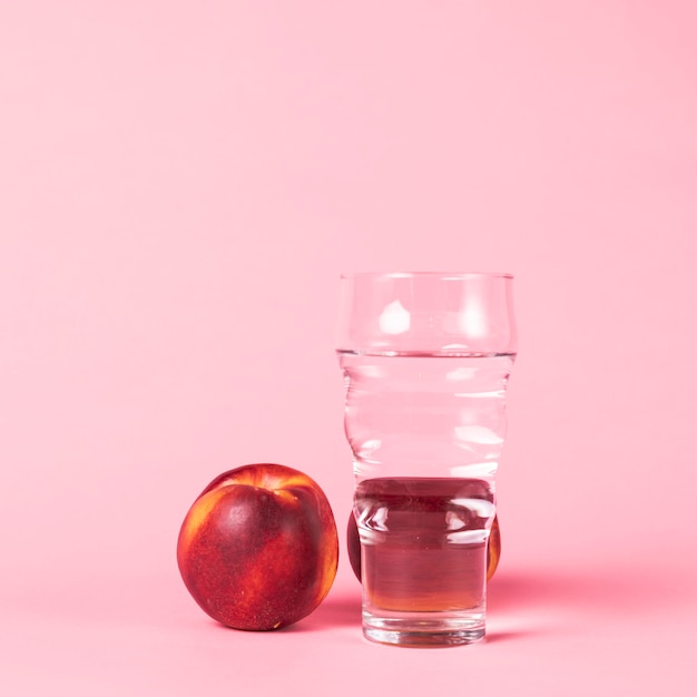 Nectarine and water on pink background