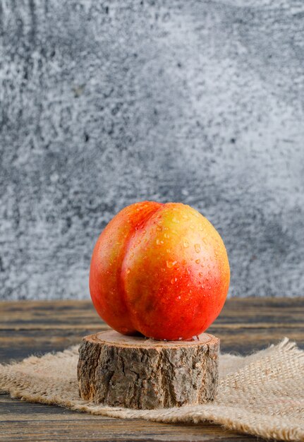 Nectarine with piece of sack, wood timber side view on wooden and grungy wall