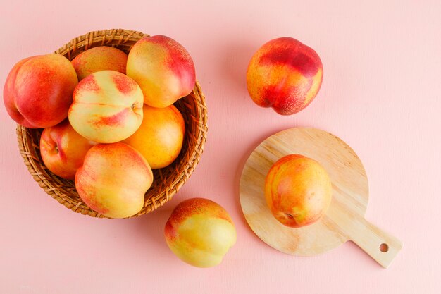 Nectarines in a basket flat lay on pink and cutting board table
