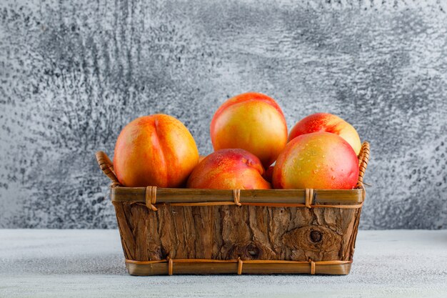 Nectarines in a basket side view on a grungy wall