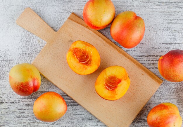 Nectarines on grungy and cutting board table, flat lay.