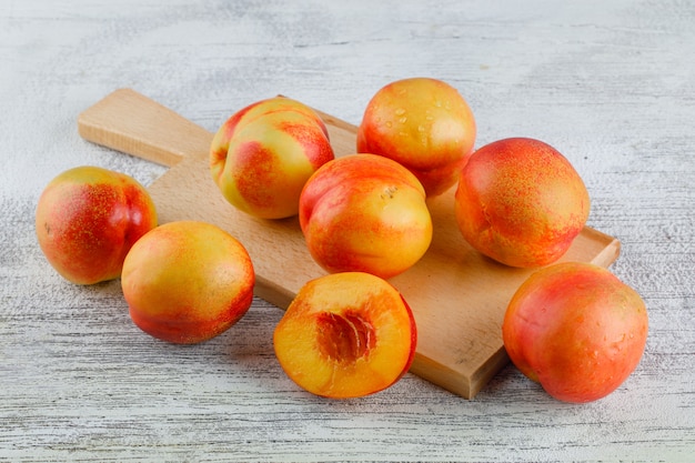 Nectarines on grungy and cutting board table, high angle view.