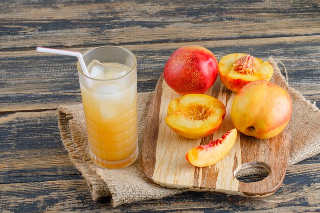 Nectarines with cutting board, juice on wooden and piece of sack