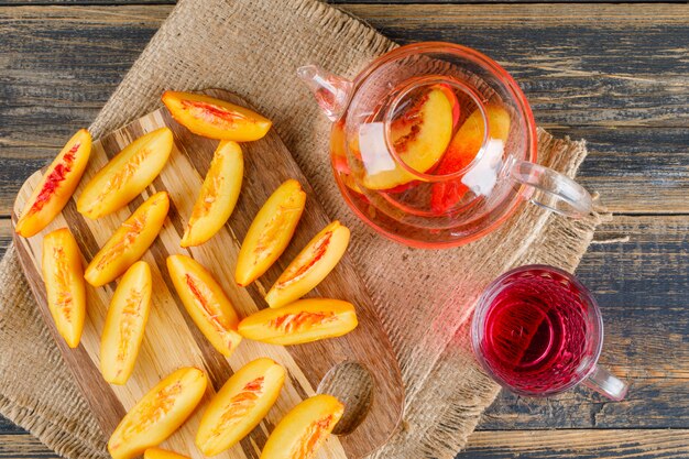 Nectarines with drink, cutting board top view on wooden and piece of sack