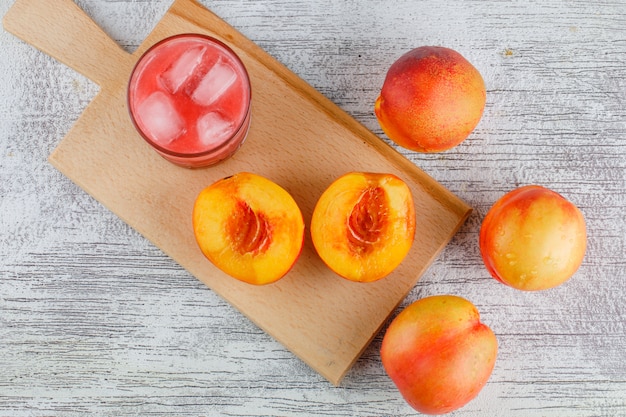 Nectarines with juice on grungy and cutting board table, flat lay.