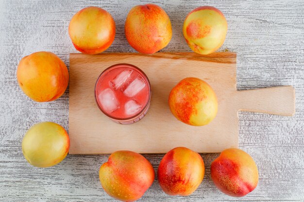 Nectarines with juice on grungy and cutting board table, flat lay.