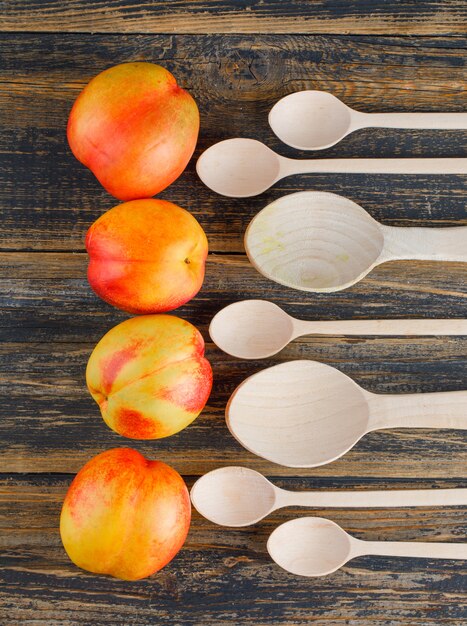 Nectarines with wooden spoons flat lay on a wooden table