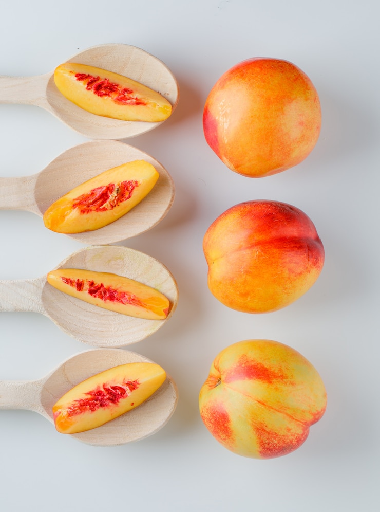 Free Photo nectarines in wooden spoons on a white table