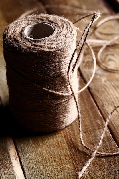 needles and bovine thread on wooden table