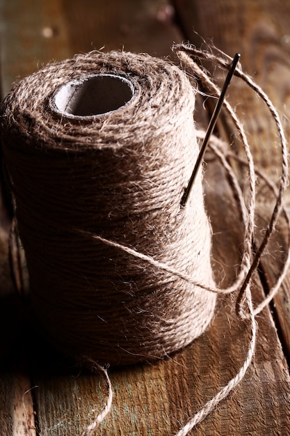 needles and bovine thread on wooden table