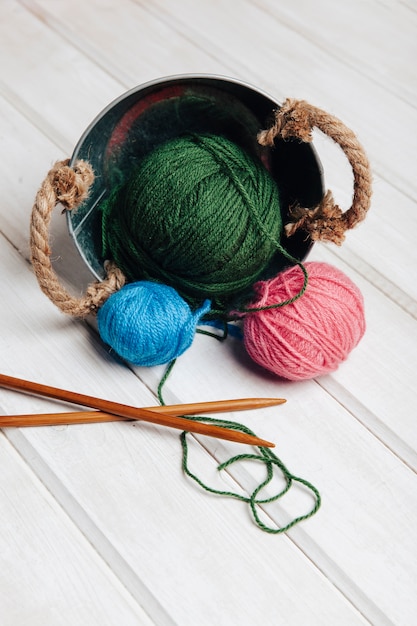 Free photo needles and wool balls in metal pot