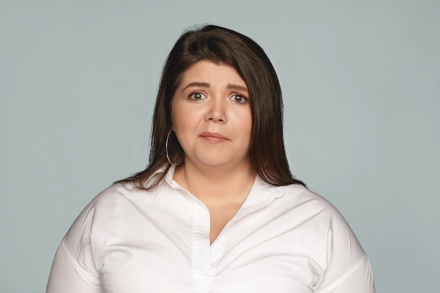 Negative human emotions, feelings, attitude and reaction. Emotional upset young dark haired female with curvy body making displeased grimace, having worried, scared or frustrated facial expression