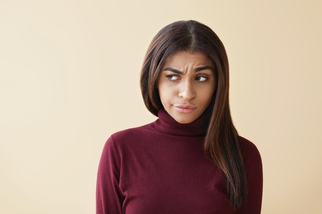 Negative human feelings and emotions. Portrait of displeased young dark skinned female dressed stylishly frowning and pouting lips after quarrel with her man, feeling offended and stressed out