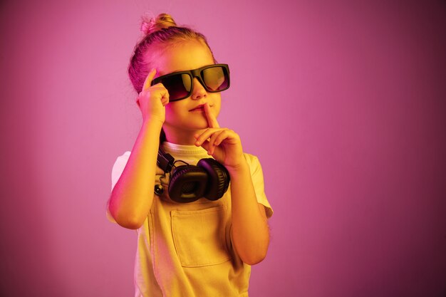 Neon portrait of young girl with headphones enjoying music and calling for silence.