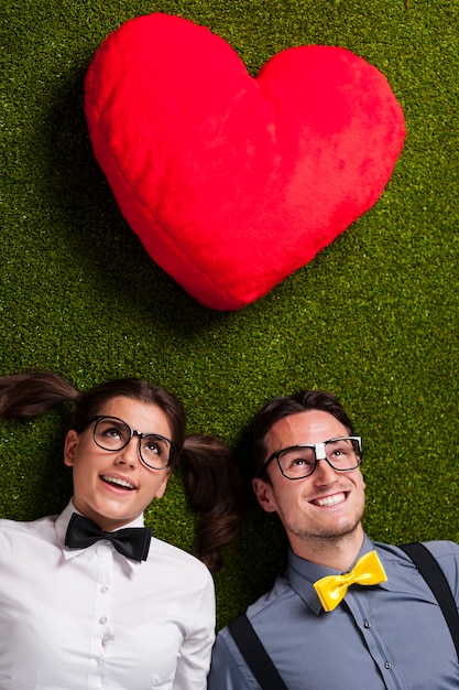 Free photo nerdy couple in love lying down on grass