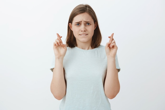 Free photo nervous hopeful good-looking woman with cute flapped ear biting lower lip anxiously and frowning looking intense while waiting important news crossing fingers for good luck, making wish