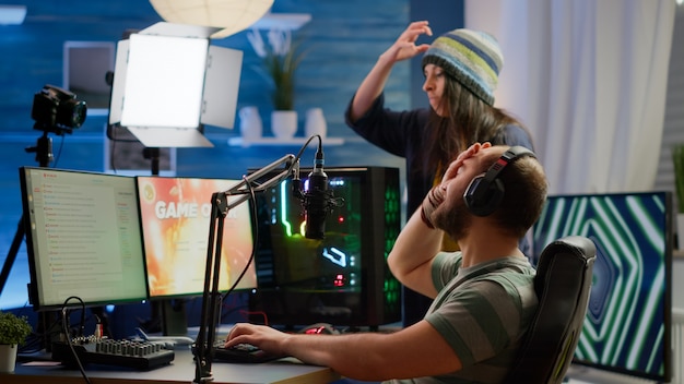 Nervous players couple losing online videogames competition using powerful computer screaming at each other. Streamer gamer playing video games with RGB keyboard performing at gaming turnament