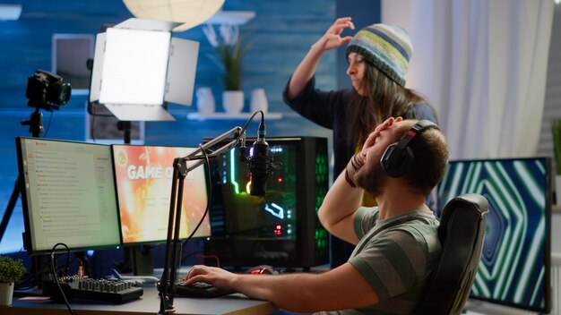 Нервные игроки пара проигрывают соревнования по онлайн-видеоиграм, используя мощный компьютер, крича друг на друга. Стример-геймер, играющий в видеоигры с RGB-клавиатурой, работает на игровом рынке