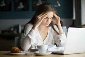 Foto gratuita mal di testa stressato nervoso dello studente femminile che studia in caffè