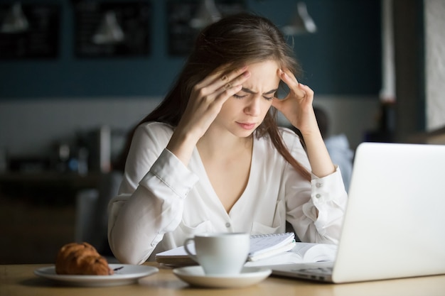 Нервно-стрессовая студентка чувствует головную боль учится в кафе