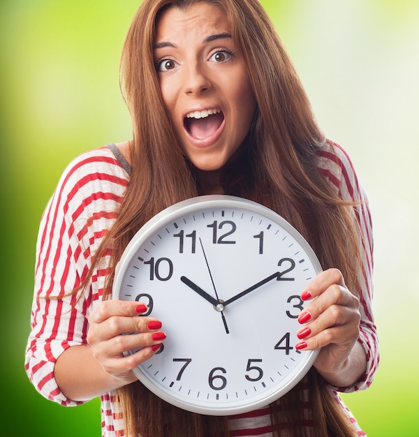 Nervous woman holding wall clock in hands. 