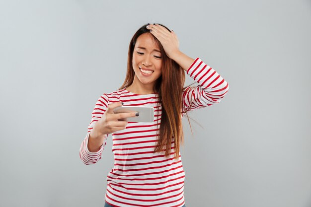 Nervous young asian lady play games by phone