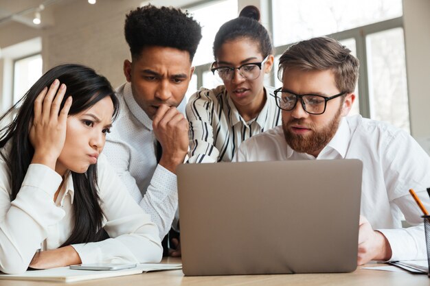 Nervous young business colleagues using laptop computer.