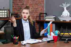 Free photo nervous young lady sitting at a table and showing the document in the office