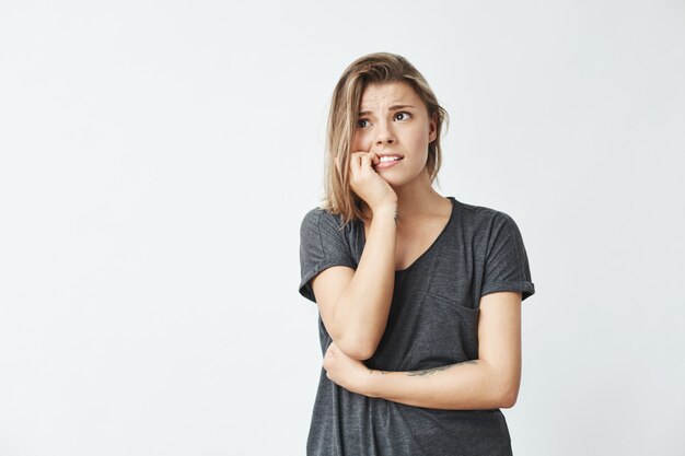 Nervous young pretty girl looking in side biting nails .