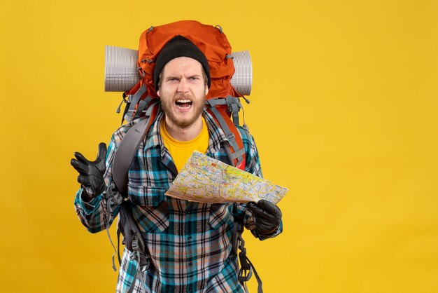 nervous young tourist with leather gloves and backpack holding map