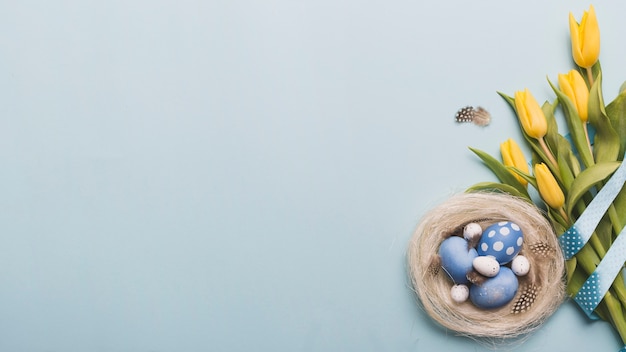 Бесплатное фото Гнездо с цветными яйцами возле тюльпанов