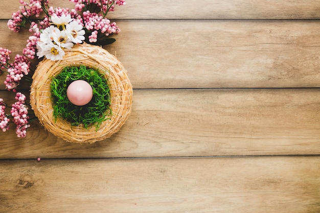 Бесплатное фото Гнездо с яйцом возле цветов