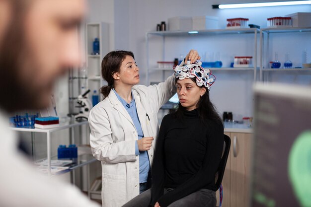 Врач невролог-исследователь регулирует сканер eeg на голове пациента, анализируя эволюцию мозга, работая над диагностикой заболеваний во время неврологического эксперимента в лаборатории высоких технологий. Доктор, объясняя томографию