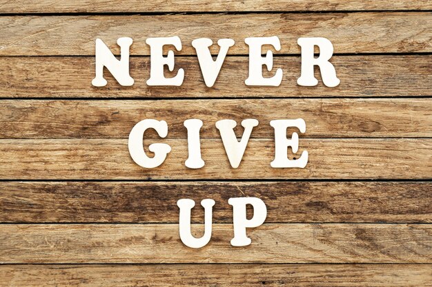 Never give up words made of wooden letters on a wooden background