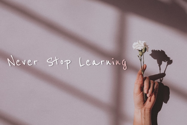 Never stop learning quote and hand holding flower
