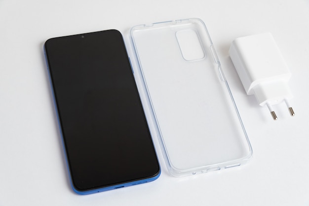Бесплатное фото Новый мобильный телефон и зарядное устройство с прозрачной крышкой на изолированном белом фоне