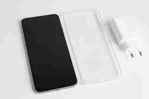 Free photo new cellphone and charger with transparent cover over isolated white background