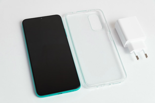 Foto gratuita nuovo cellulare e caricabatterie con coperchio trasparente su sfondo bianco isolato