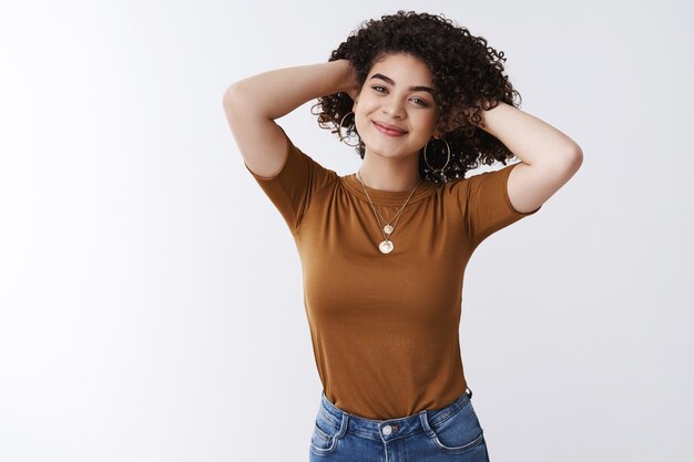 New haircut feeling fresh confident. Attractive cheerful mixed-race girl playing curly dark hair smiling satisfied feel relaxed satisfied happy got awesome hairstyle standing white background