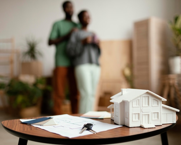 New home keys and plan on table with defocused couple