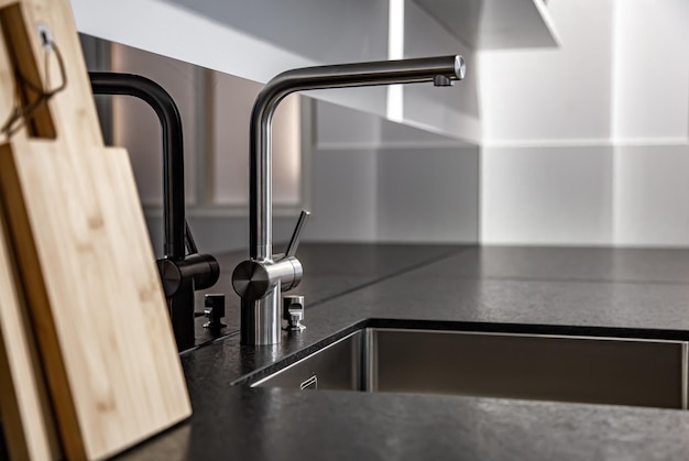 New modern steel faucet and kitchen room sink close up