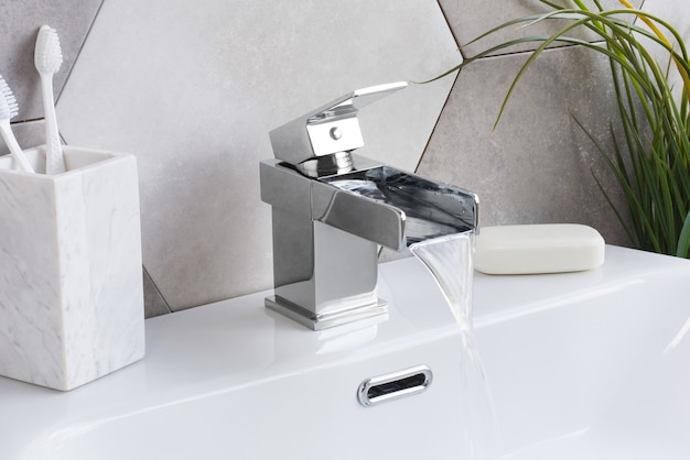 Новый и современный стальной смеситель с керамической раковиной в ванной комнате.