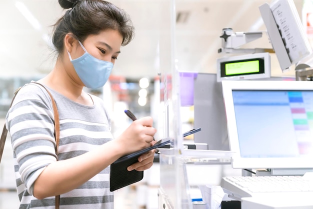무료 사진 코비드 전염병 이후의 새로운 정상 아시아 여성 지불 진행은 백화점 계산대에서 스마트하인 무현금 및 비접촉식 새로운 라이프스타일 쇼핑으로 스캔 앱을 구입합니다.