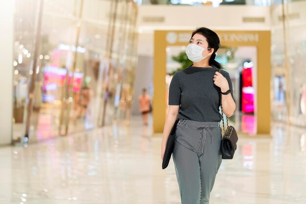 covid 전염병 젊은 비즈니스 아시아 여성이 코로나 바이러스 covid19 확산 후 중앙 광장 백화점 쇼핑몰에서 걷는 안면 보호 마스크를 착용한 후 새로운 일상